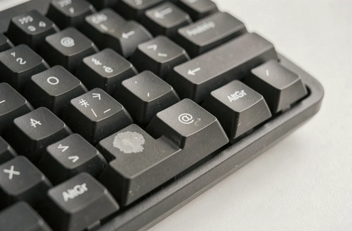 Gros plan sur un clavier AZERTY mécanique montrant les caractères spéciaux et symboles pour réseaux sociaux