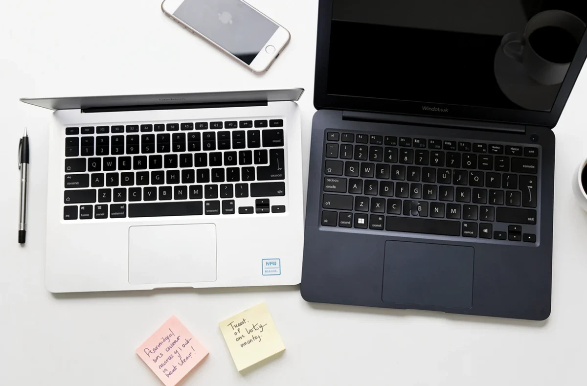 Comparaison produit MacBook Air et PC Windows ultrabook en vue à plat sur surface blanche avec accessoires de bureau